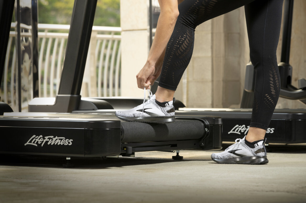 Kvinna knyter skon på ett löpband från Life Fitness