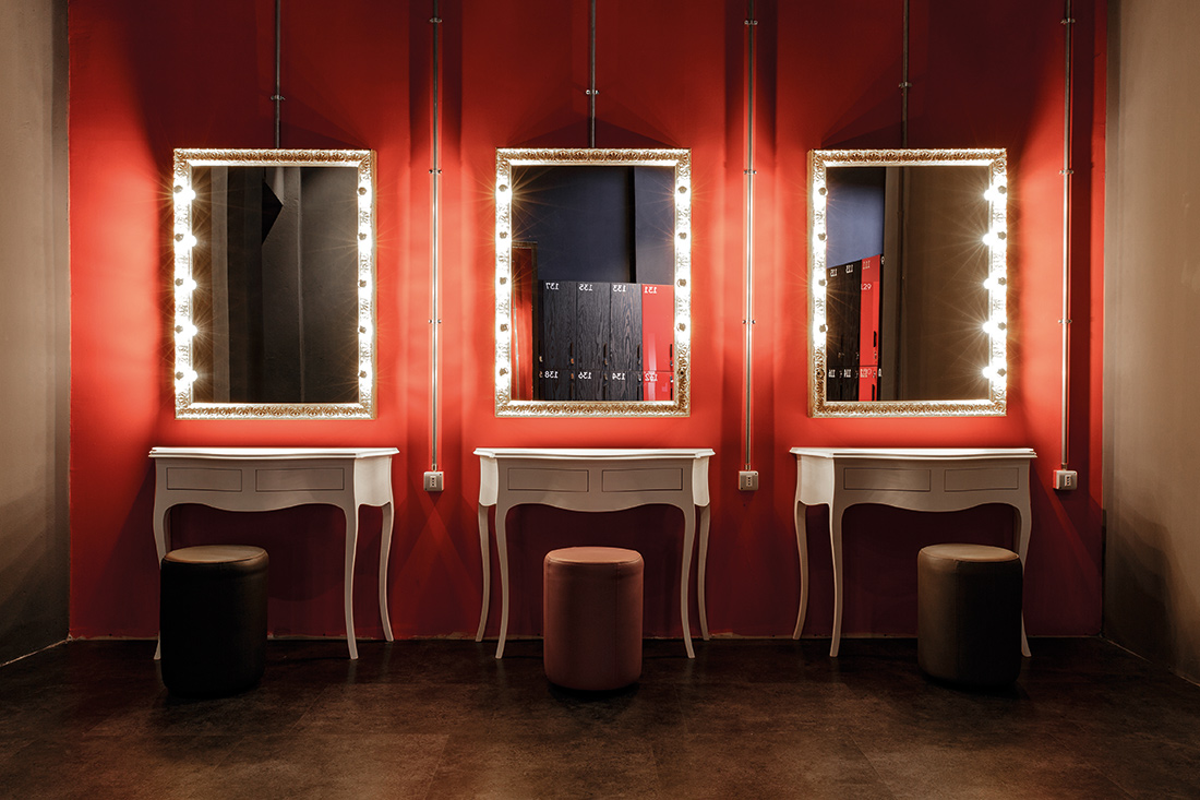 Den röda väggen mot retrodesign på speglar och bord med supermodern belysning ger en skön krock.
