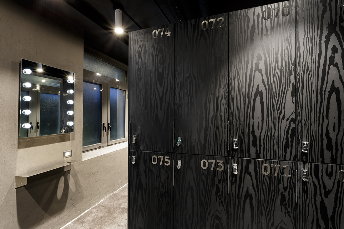 Omklädningsrum med eleganta svarta skåpluckor och speglar med belysning från Fit Interiors